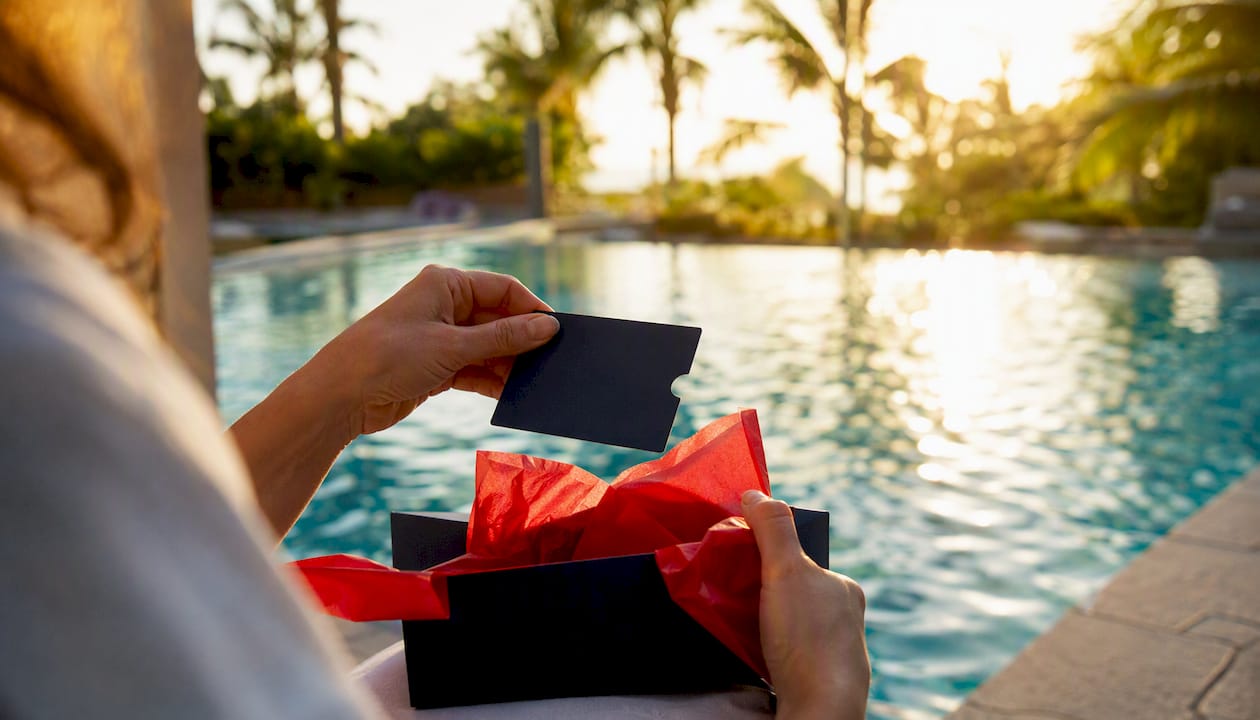 travel gift card fees: what you need to know in 2026 3 hands unboxing travel gift card at resort pool