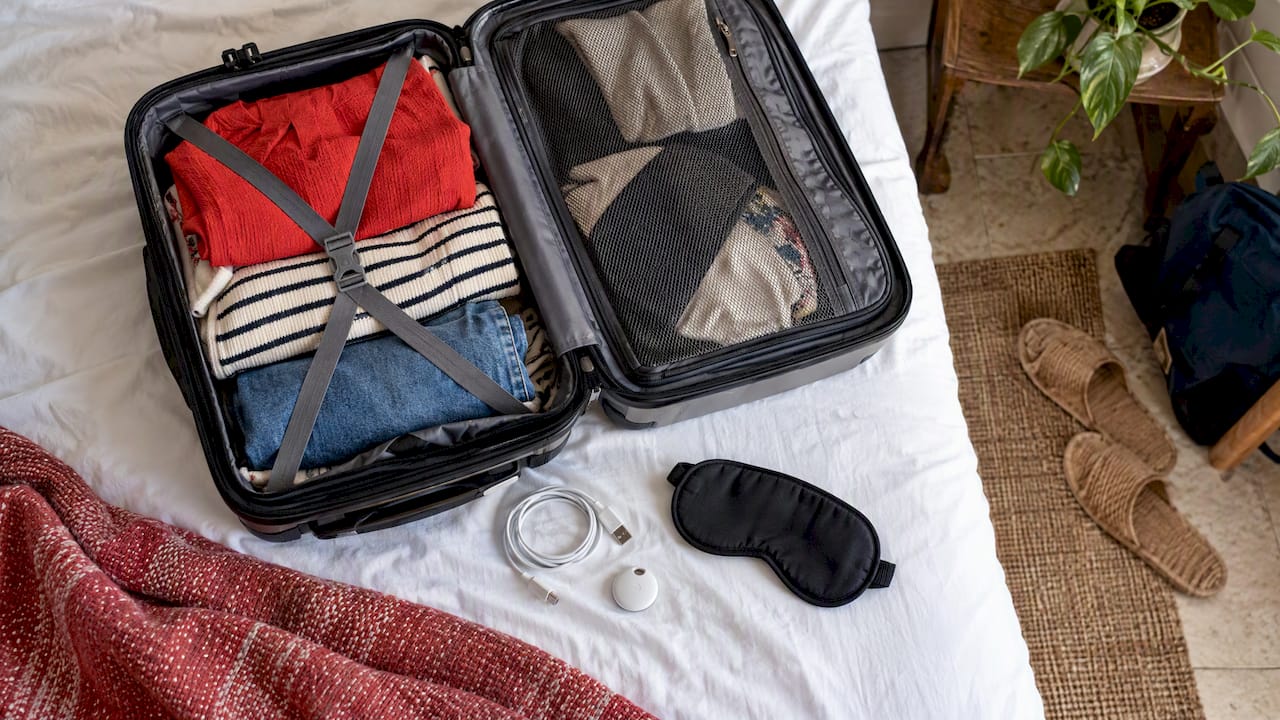 Compact travel essentials beside an open carry-on